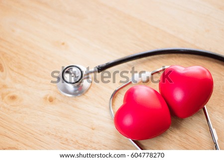 Red heart and a stethoscope on wooden table