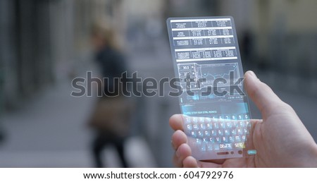 A businessman in the city,use the transparent phone with the latest technology to control finance and the markets of the financial bag. Concept:technology,business, immersive technology and future