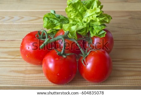 Bunch of ripe red tomatoes with green salad on the old wooden table