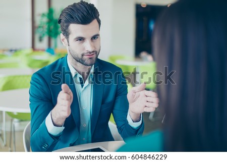 Photo of two young workers having a meeting in a restaurant. Businessman gesturing and making hand frame