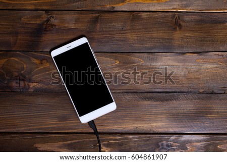 White mobile phone wooden background wooden charging cable, top view