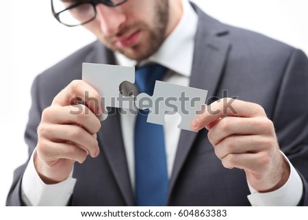 Close up of man trying to connect puzzle pieces.