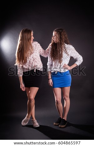 studio portrait of Beautiful young caucasian women sisters best friends bff isolated on black background, girls in short skirts, posing fashion, hugs
