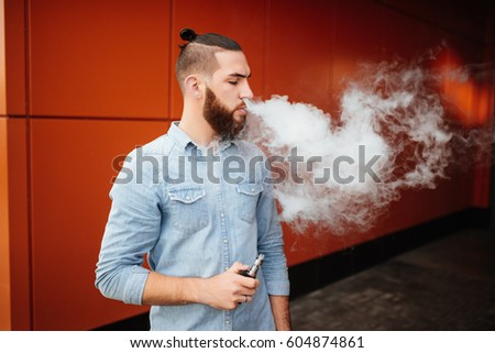 The model vaper vaping a vaporizer outdoors. Safe smoking. Young vaper.