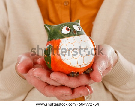 Close up picture of an elderly woman holding an owl as the symbol of wisdom