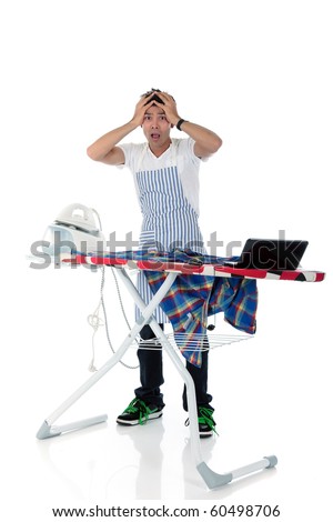 Young stressed Nepalese man with iron and laptop on the ironing-board. Studio shot, white background.