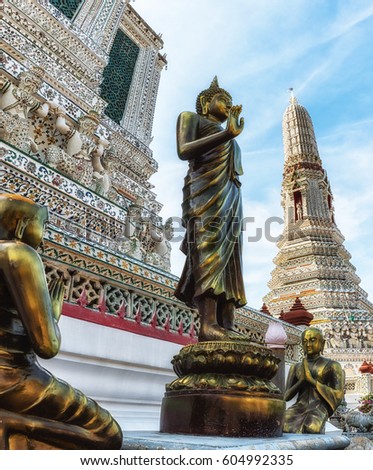 Thai buddha and praying monks sculpture with Prang (spire) at Arun Ratchawararam temple in Bangkok, Thailand
