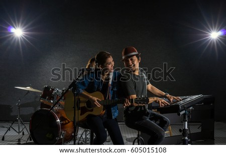 Musician duo band singing a song and playing music instrument with Fellow band musicians on black background with spot light and lens flare, musical concept