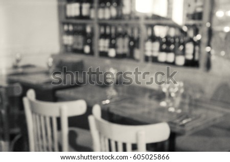 Blurred photo of Parisian cafe interior with wine bottles at background. Paris (France). Black and white.