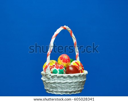 Blue background. Wicker basket with Easter eggs with hand-drawn flower pattern