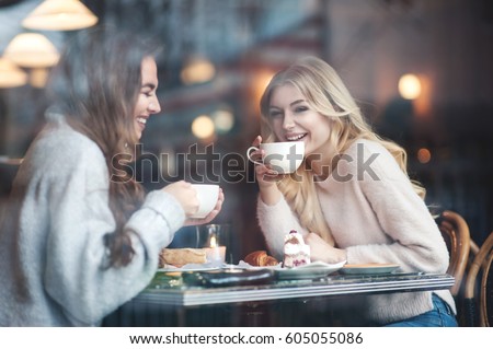 Two girl friends drinking coffee in the cafe Royalty-Free Stock Photo #605055086