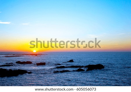 Backlit at sunset on the beach with sea water and cloudy sky in the city of Cadiz, Andalusia. Spain 