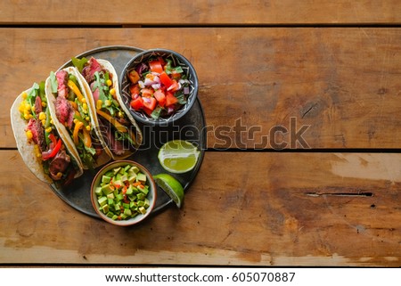 Mexican pork tacos with vegetables and salsa. Tacos al pastor on wooden rustic background. Top view, flat, overhead. Copy space and text area.