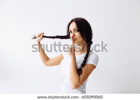Beautiful brunette model girl with long braid hair. Hairstyle pigtail. Red lips and nails manicure .Woman holds a finger on her mouth. Secret concept.