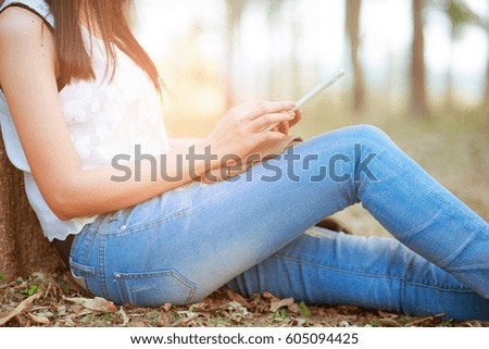 Young woman using tablet sitting in park.