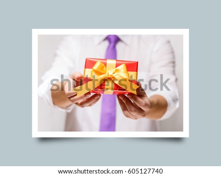 Male hands holding a gift box. Present wrapped with ribbon and bow. Christmas or birthday red package. Man in white shirt and necktie. Photo frame design with shadow.