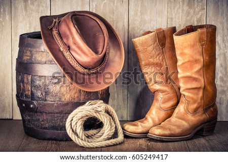 Wild West retro leather cowboy hat, old boots and oak barrel. Vintage style filtered photo