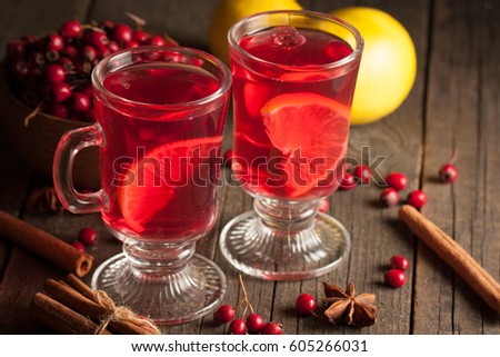 Two cups of red hot tea drink with fruits and spices on a wooden background. Mulled wine with cinnamon, anise and red berries. Winter hot drinks concept.