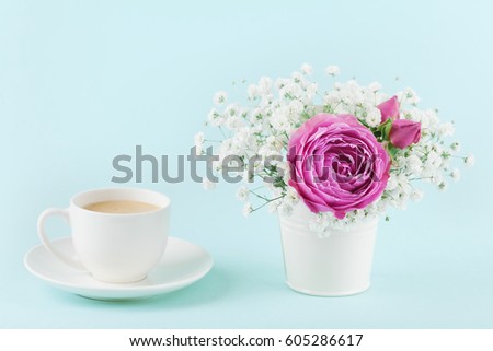 Beautiful pink rose flower and gypsophilla in vase and cup of coffee on turquoise vintage table for cozy breakfast