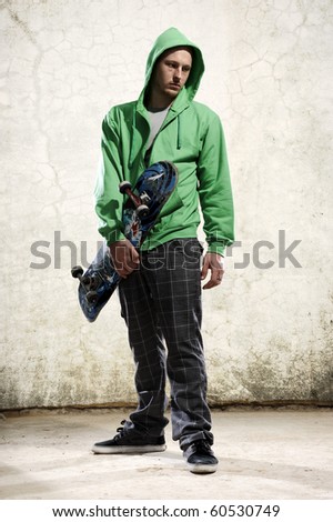 Youth stands with skateboard and green hoodie