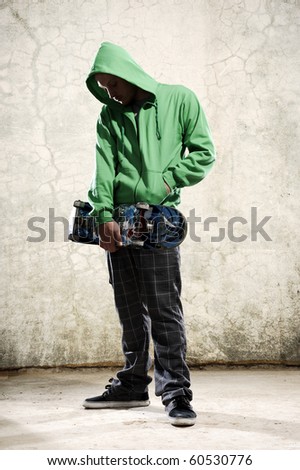 Youth stands with skateboard and green hoodie