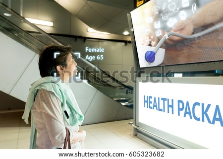 Intelligent Digital Signage marketing and face recognition concept. Old woman watch interactive artificial intelligence digital advertisement about healthcare package in retail shopping Mall.