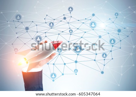 Close up of a hand of a businessman holding a toy rocket against a gray wall with a network sketch. Toned image.
