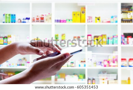 Man use mobile phone, blur image of drugstore as background.