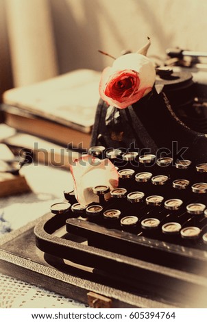 Vintage typewriter with pink rose , old books on table. sepia photo