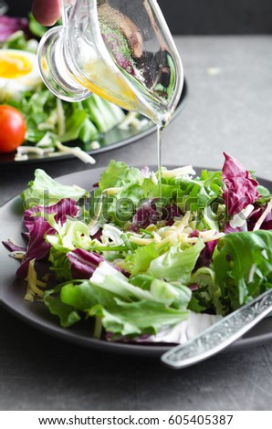 Fresh salad meal and a gravy boat with pouring sauce Royalty-Free Stock Photo #605405387