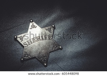 Sheriff badge on gray leather texture background. Macro shot.