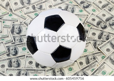Leather soccer ball on the field of background paper dollar bills 
