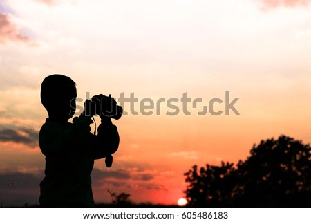 cute little boy takes photos of nature at sunset
