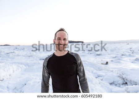 A Man posing at camera with an iceberg in the background