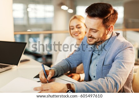 Young business couple signing a contract Royalty-Free Stock Photo #605497610