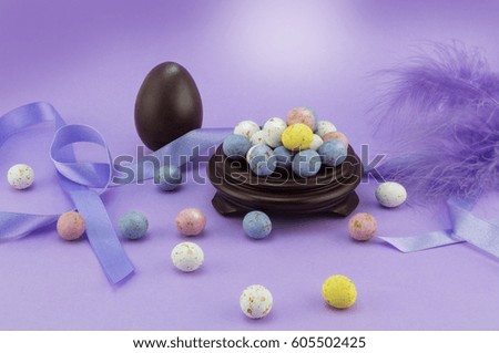 Lilac/ mauve Easter egg background with many colored speckled eggs