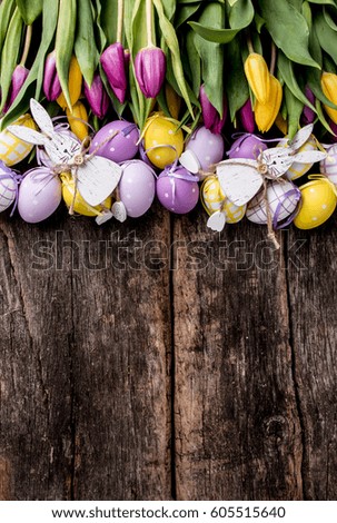 Easter eggs on wooden background. Spring concept on plank. Yellow  and purple eggs with nature decoration. 
