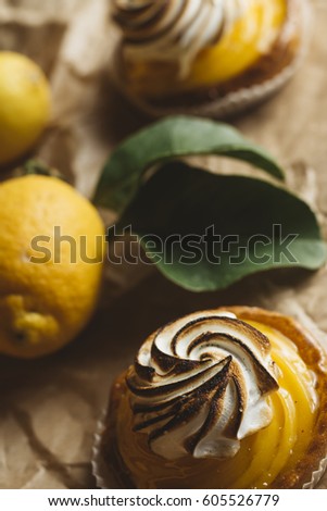 Lemon pie on the table with citrus fruits. Traditional french sweet pastry tart. Delicious, appetizing, homemade dessert with lemon cream. Copy space, closeup. Selective focus. Toned.