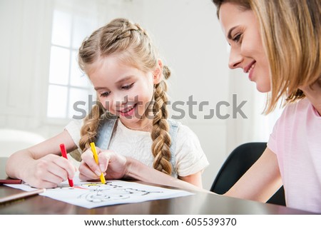 Happy mother and daughter drawing at home