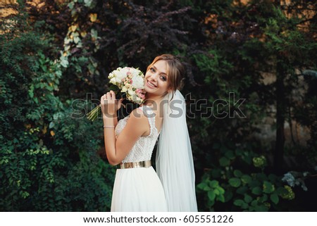 Bride holds her tender wedding bouquet before her face