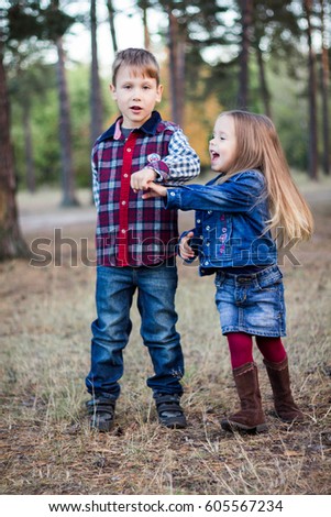 The boy is holding the girl's hand. A boy is dancing with a girl. Children in the forest