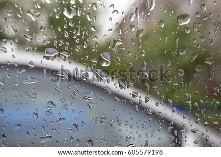 Drops of rain on the car glass with blurred trees on the background