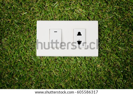 Electric plug outlet and switch on green grass nature background save eco environment concept