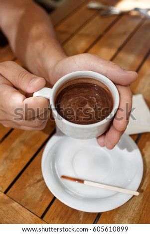 Man hands holding cup of coffee at cafe outdoors summer. Male drink cappuccino in restaurant closeup. Coffee time and breakfast. Man with mug of hot chocolate enjoying life in cafe 