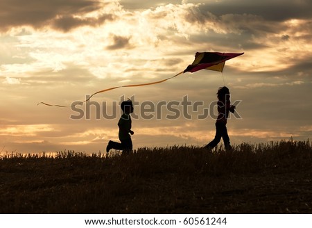 Two children enjoy flying a kite during sunset. Royalty-Free Stock Photo #60561244