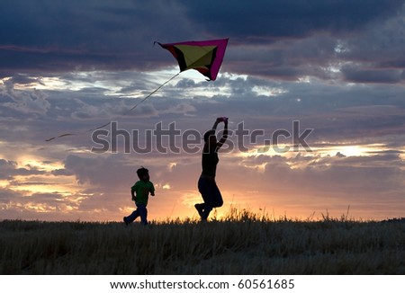 A mother runs with a kite while the son follows behind during sunset. Royalty-Free Stock Photo #60561685