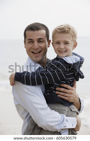 Father holding son in arms on beach