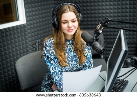Young woman radio host in the studio with microphone and wearing a headphones