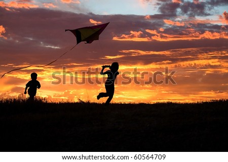 A brother and sister getting a kite to fly suring sunset. Royalty-Free Stock Photo #60564709