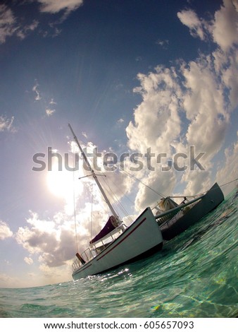 Angled Photo of a Catamaran on the Caribbean Ocean - with Clear, Aqua Colored Water and a Bright, Cloudy Afternoon Sky